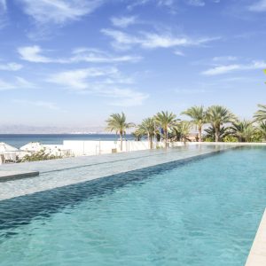 Infinity Pool with Red Sea View and greenery.